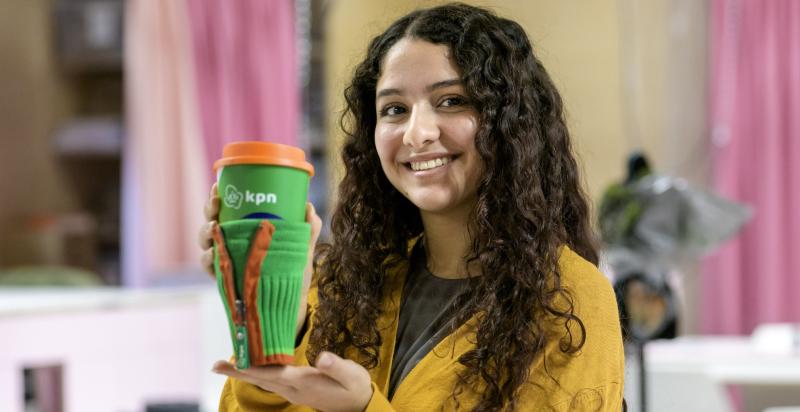 studente van Zadkine Beauty & Fashion College houdt koffiebekerverwarmer omhoog