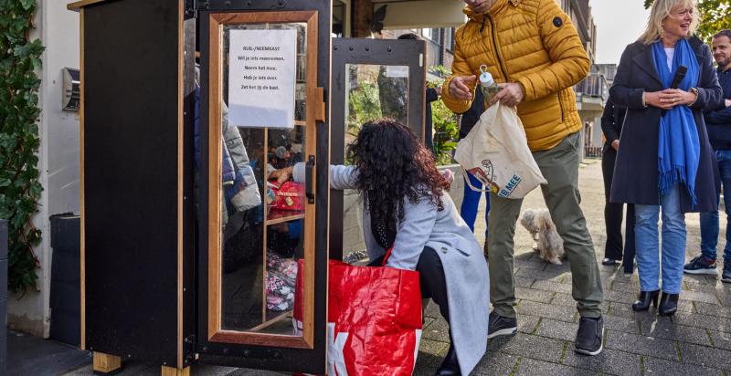 Mensen plaatsen spullen in een weggeefkast