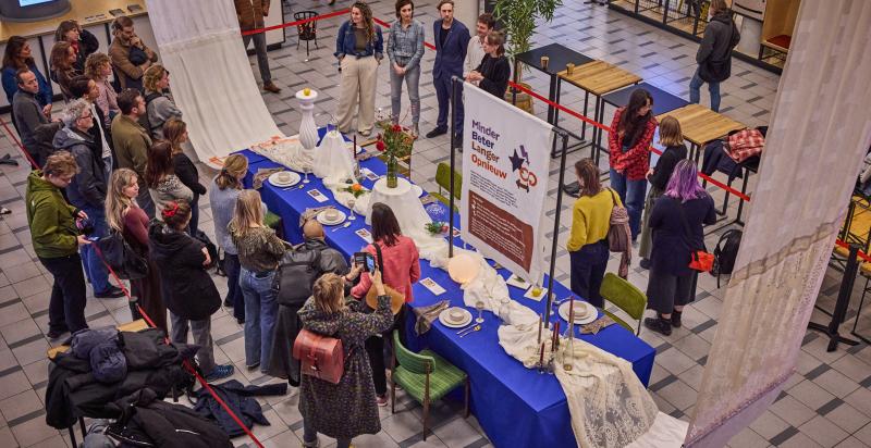 Opening van tentoonstelling Minder, Beter, Langer, Opnieuw achter een grote gedekte tafel met blauw tafelkleed.