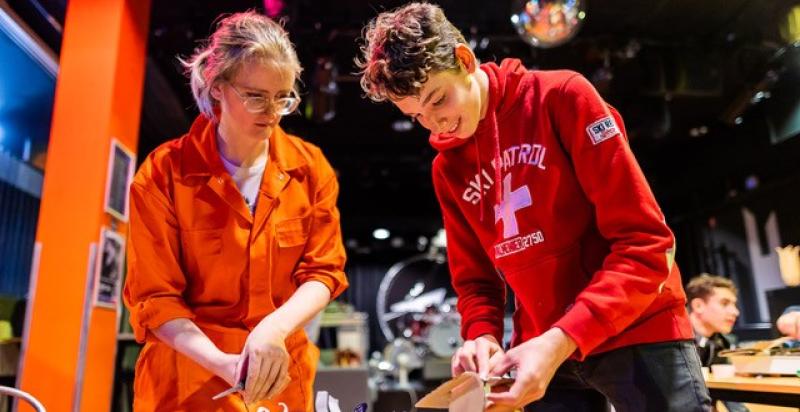 Een vrouw begeleidt een jongen aan een tafel met een creatieve creatie die hij zelf ontworpen heeft.