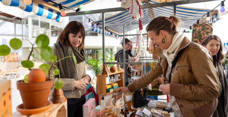 Vrouw kijkt naar producten bij een marktkraam in BlueCity tijdens het evenement Changez.