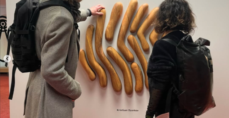 bezoekers raken een houten wandobject aan