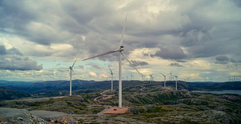 Windturbines verspreid over een uitgestrekt, rotsachtig heuvellandschap onder een zwaarbewolkte lucht.