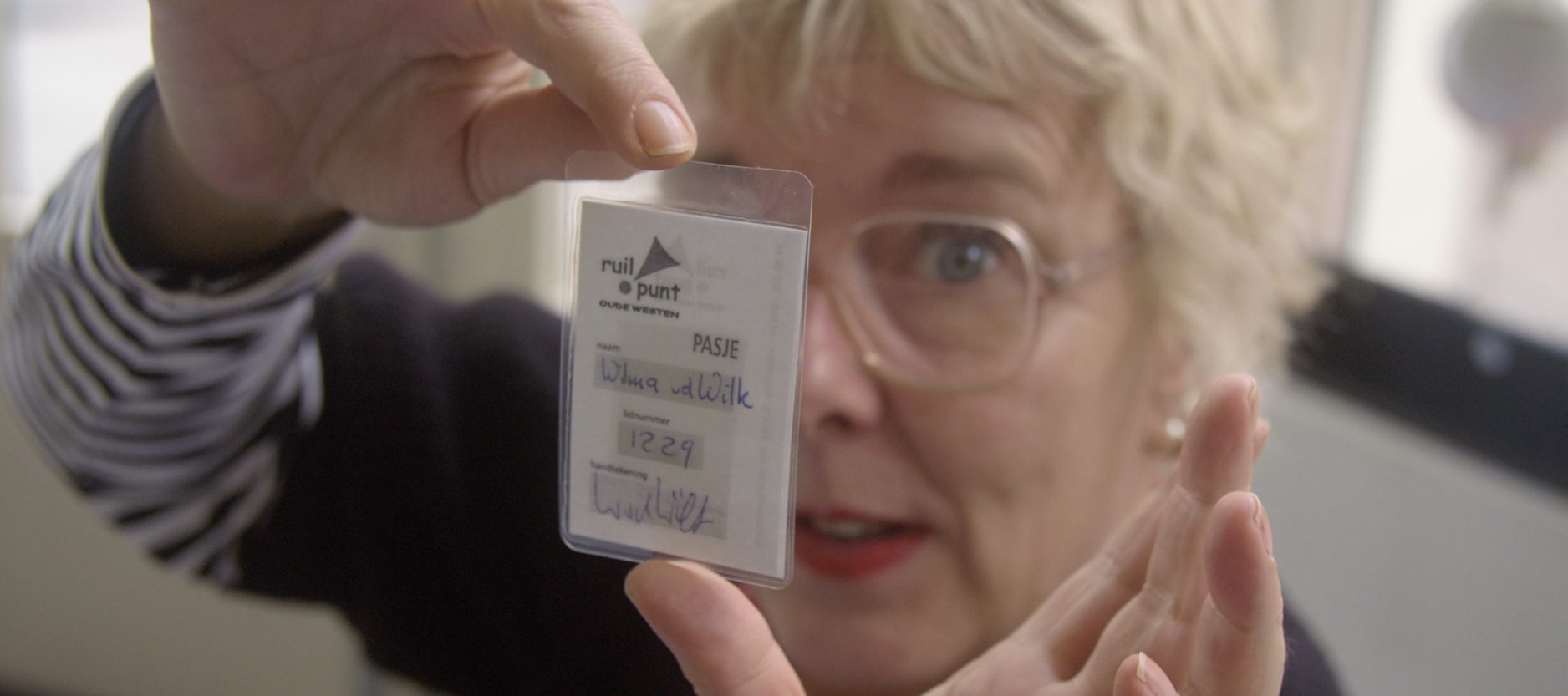 close-up foto van Wilma Kruger, voor haar gezicht houdt zij haar lidmaatschap pas van het ruilpunt.