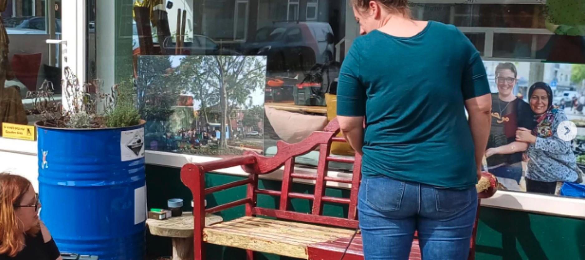 Op de foto twee personen die meubels aan het opknappen zijn op de stoep voor Gouwe Klouwe.