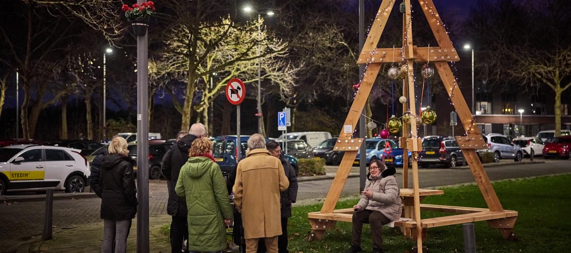 Een aantal Rotterdammers komen samen bij een circulaire kerstboom van hergebruikt hout.