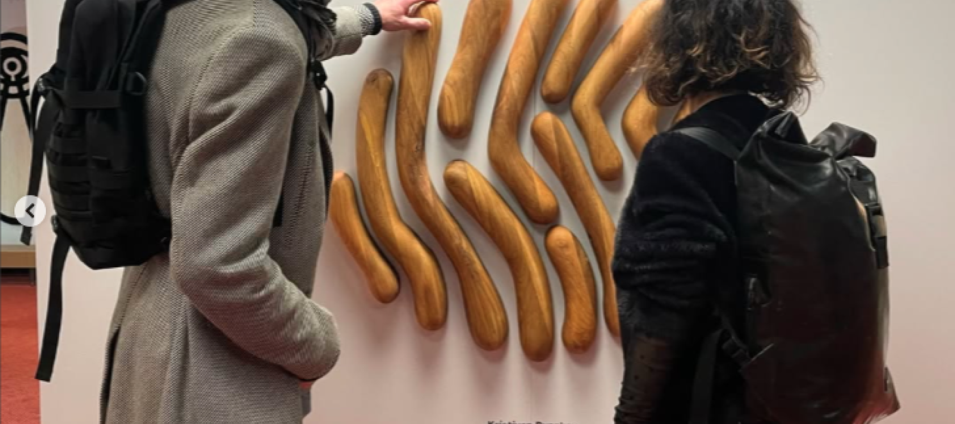 bezoekers raken een houten wandobject aan