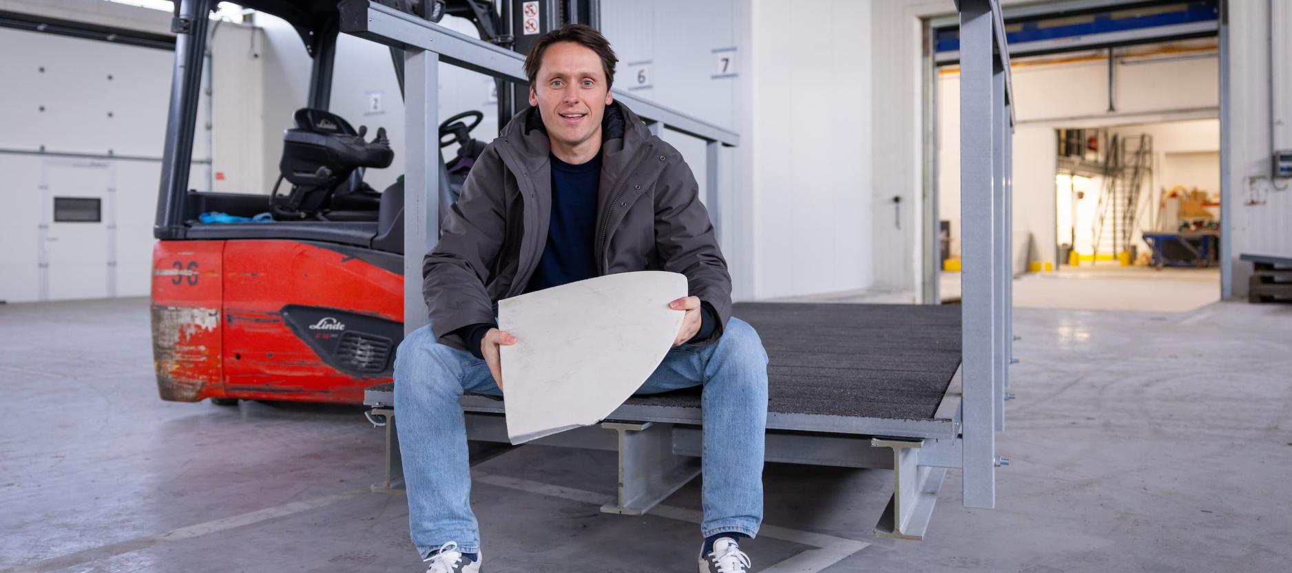Circulair ondernemer Jochem Cuppen zit in een bedrijfshal met een stuk biocomposiet in zijn handen