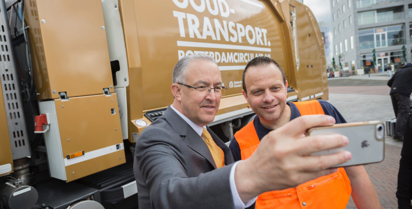Op de foto burgemeester Aboutaleb en de chauffeur van het goudtransport, een gouden vuilniswagen. Ze nemen een selfie met op de achtergrond het goudtransport.