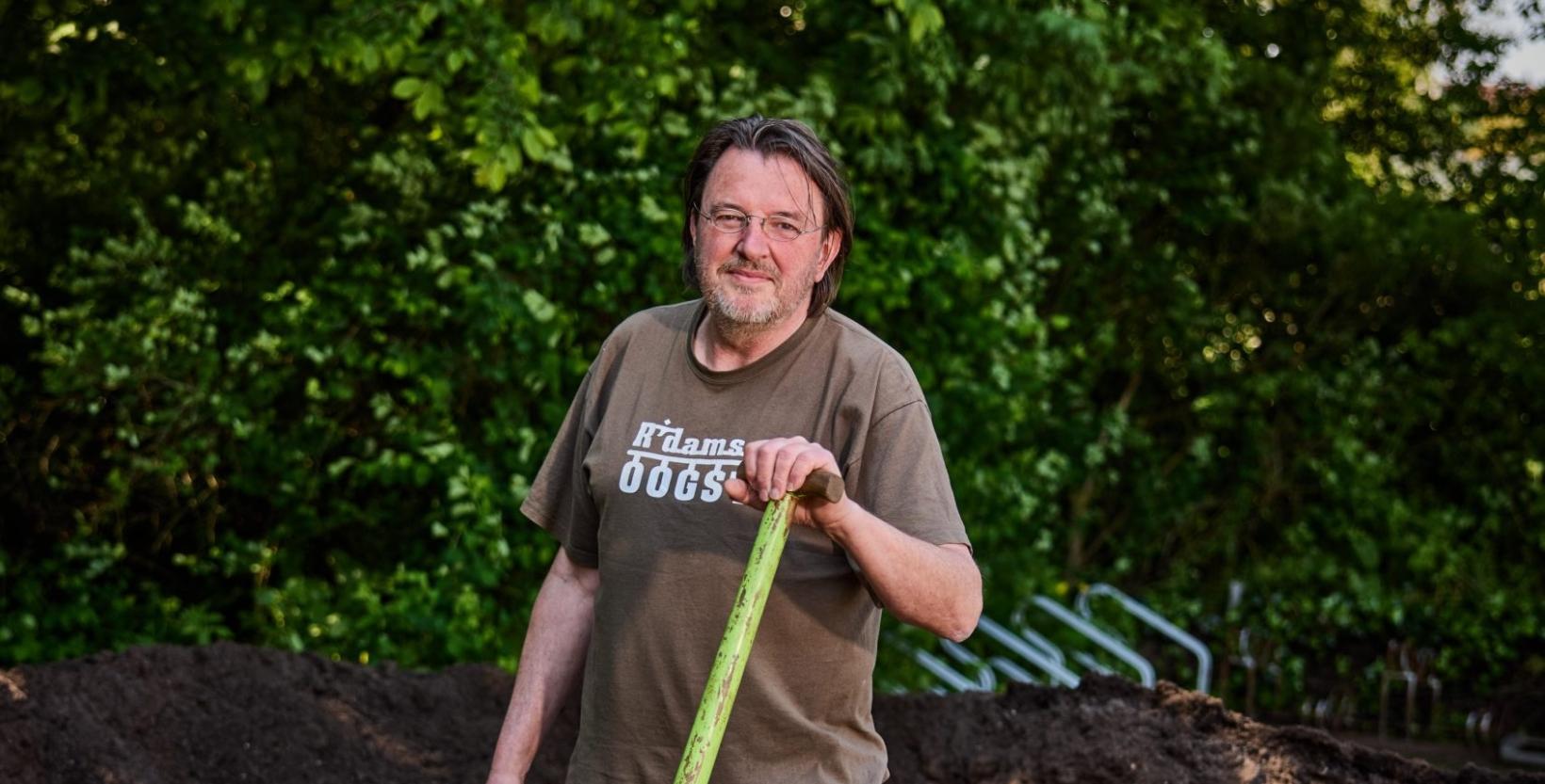 geposeerde foto van man in de tuin met een schep in zijn hand.
