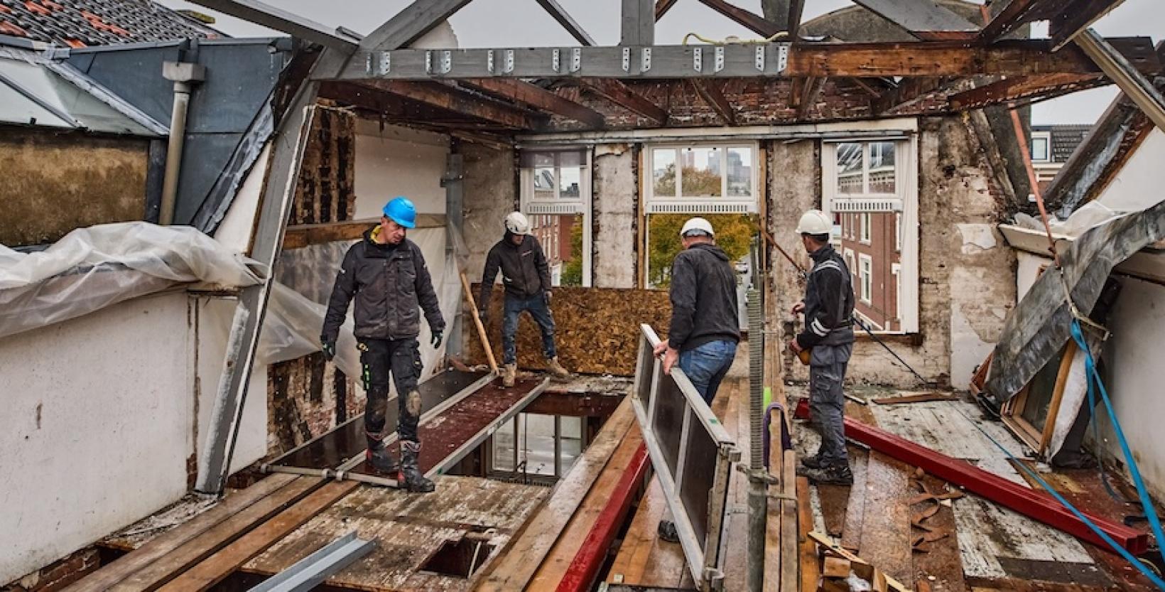 vier bouwvakkers met helmen aan het werk van de bovenste verdieping van slooppand.