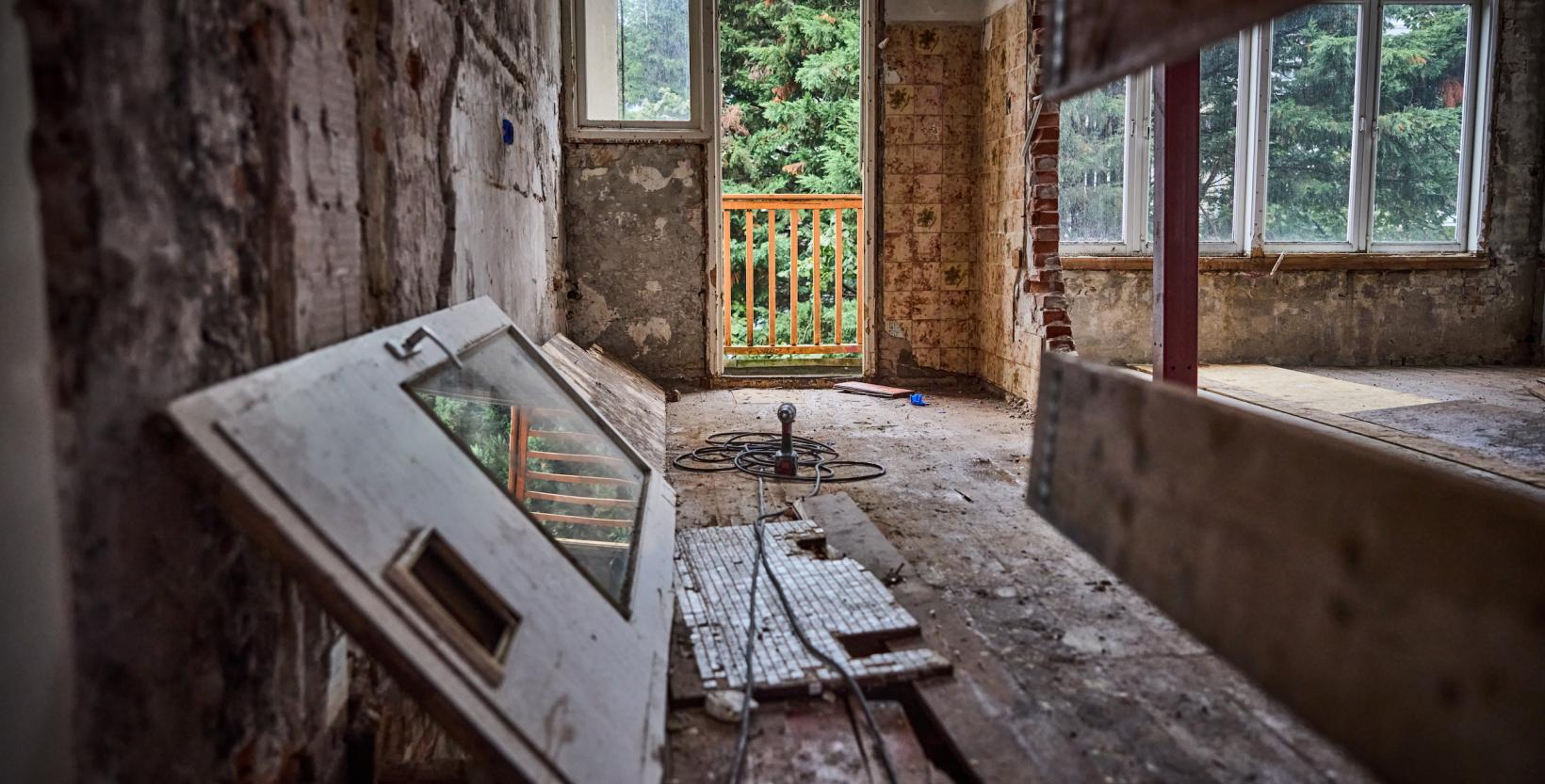 interieur van een kaal slooppand, op de voorgrond ligt een deur op zijn kant.