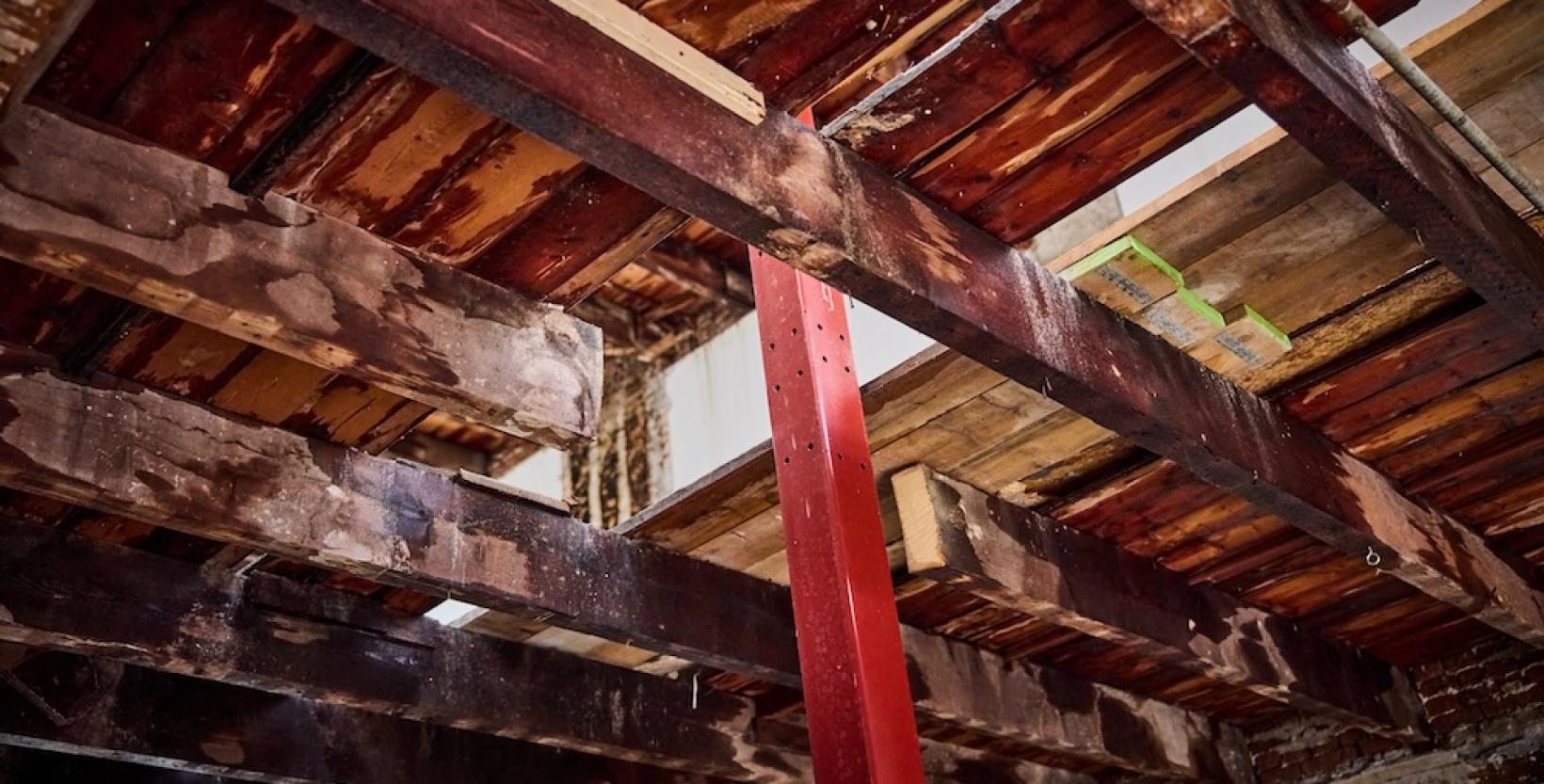 rode ijzeren balk door een plafond van houten planken