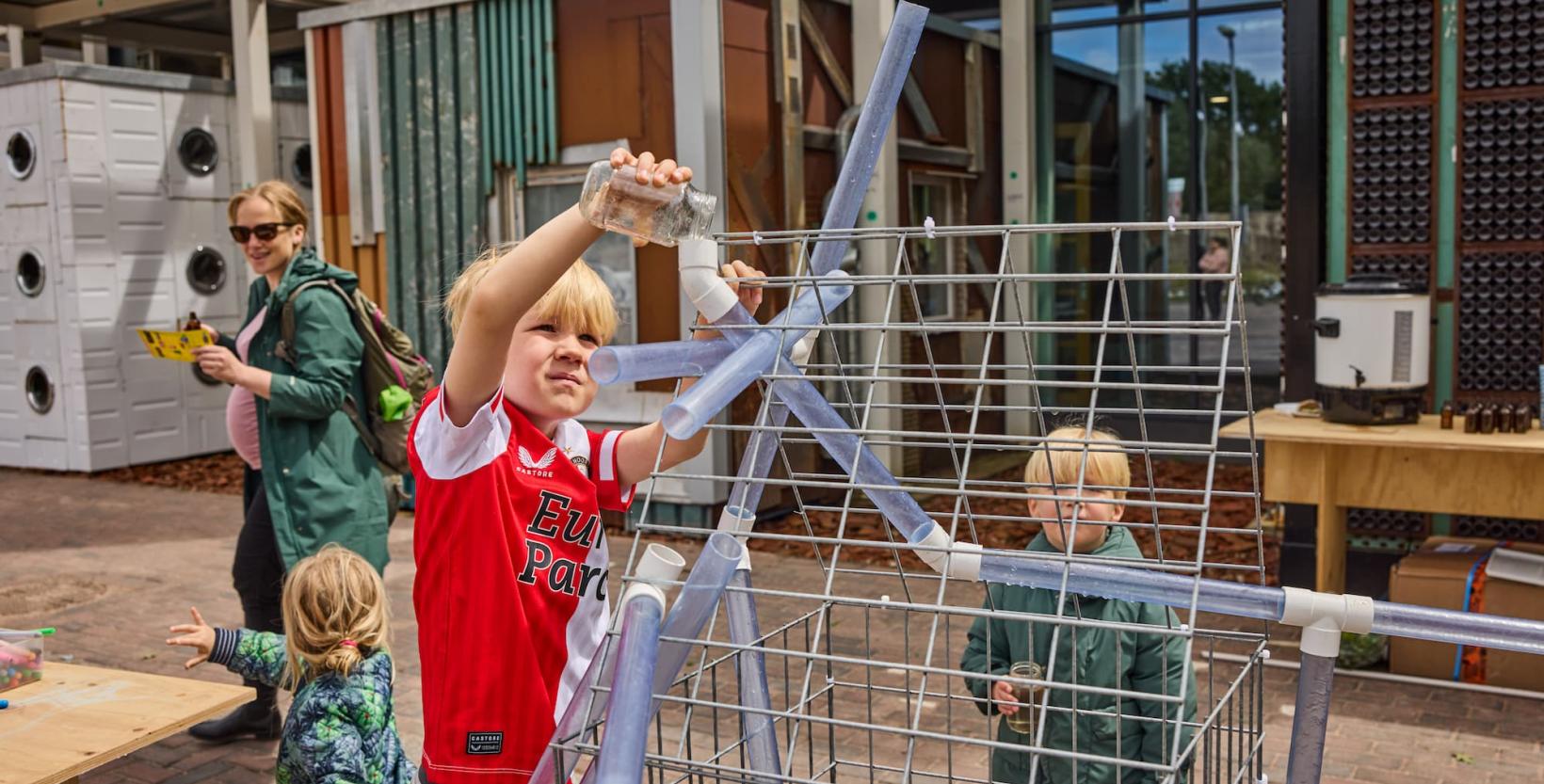 Twee kleine kinderen werken aan een opstelling om zelf water te zuiveren.