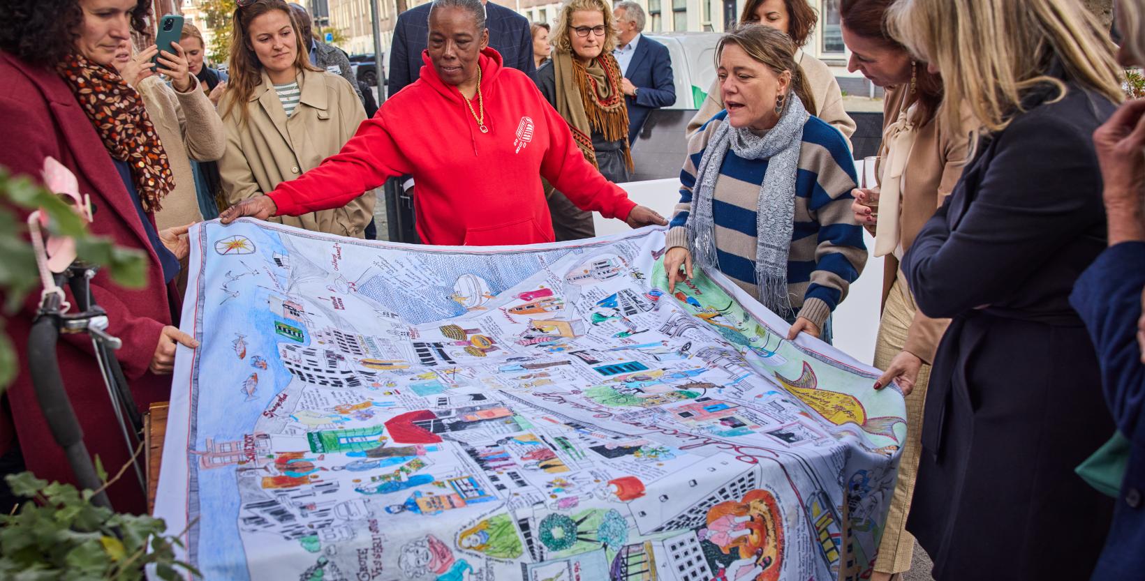 Een groep bewoners uit Delfshaven staat om een groot doek waarop allerlei buurtinitiatieven zijn getekend.