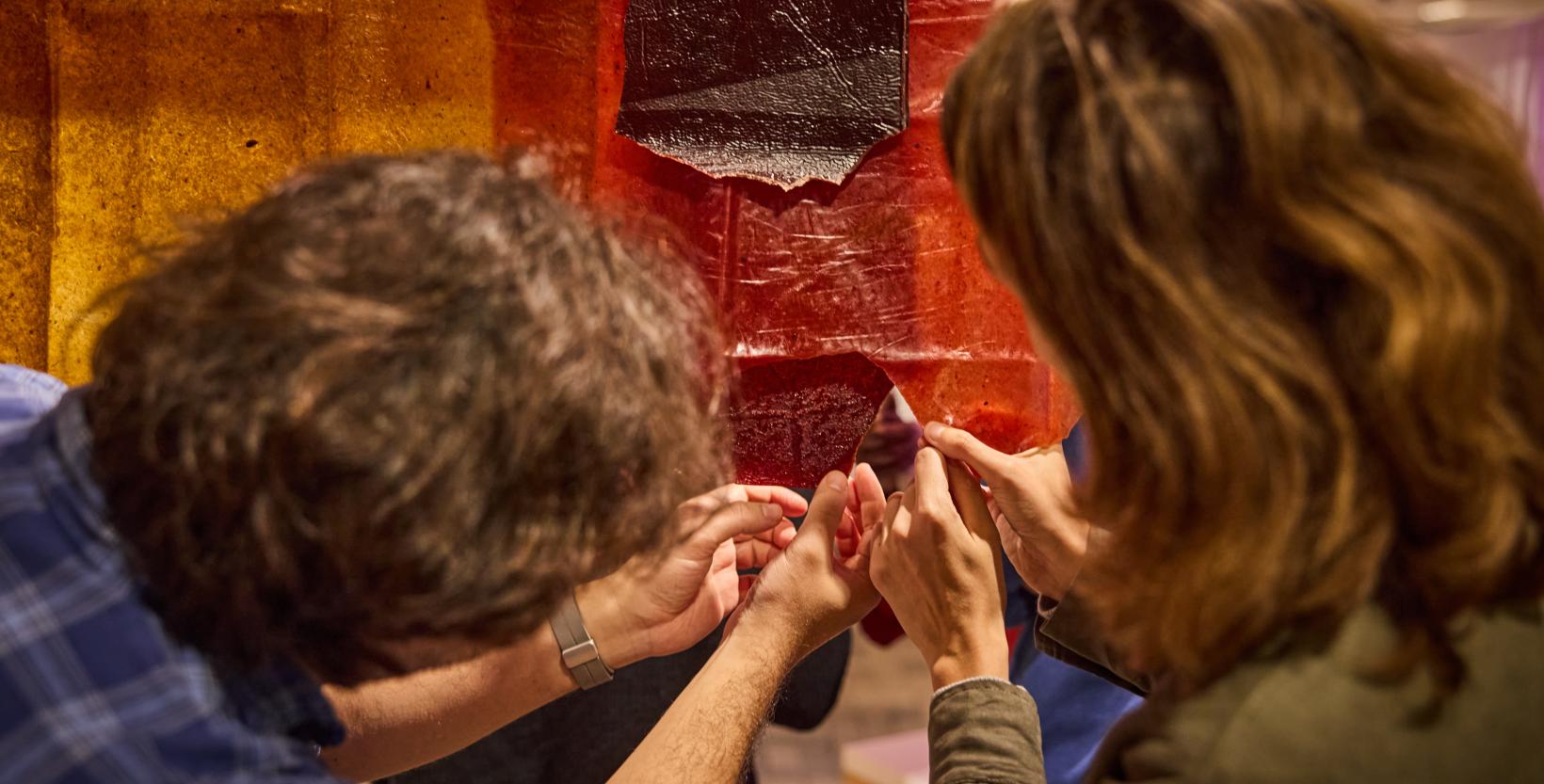 Man en vrouw scheuren iets van hangende gekleurde vellen